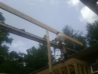 Carpenter setting a ridge beam over a new addition frame — Ice Dam Removal by Roofing Brothers in Cornville