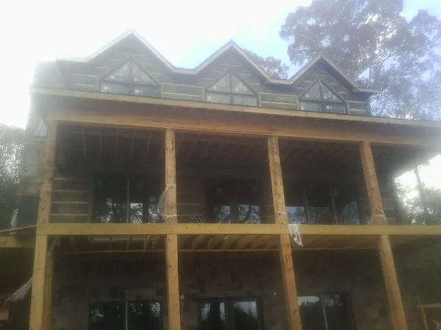Dormers and porch framing on a large log home under construction — Roof Coating work by our crew in Cornville