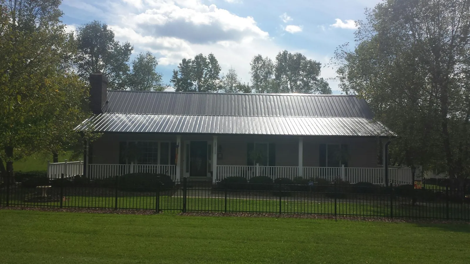 Gray metal roof on a brick ranch with a full width front porch — Gutter Guard Installation work by our crew in Cornville