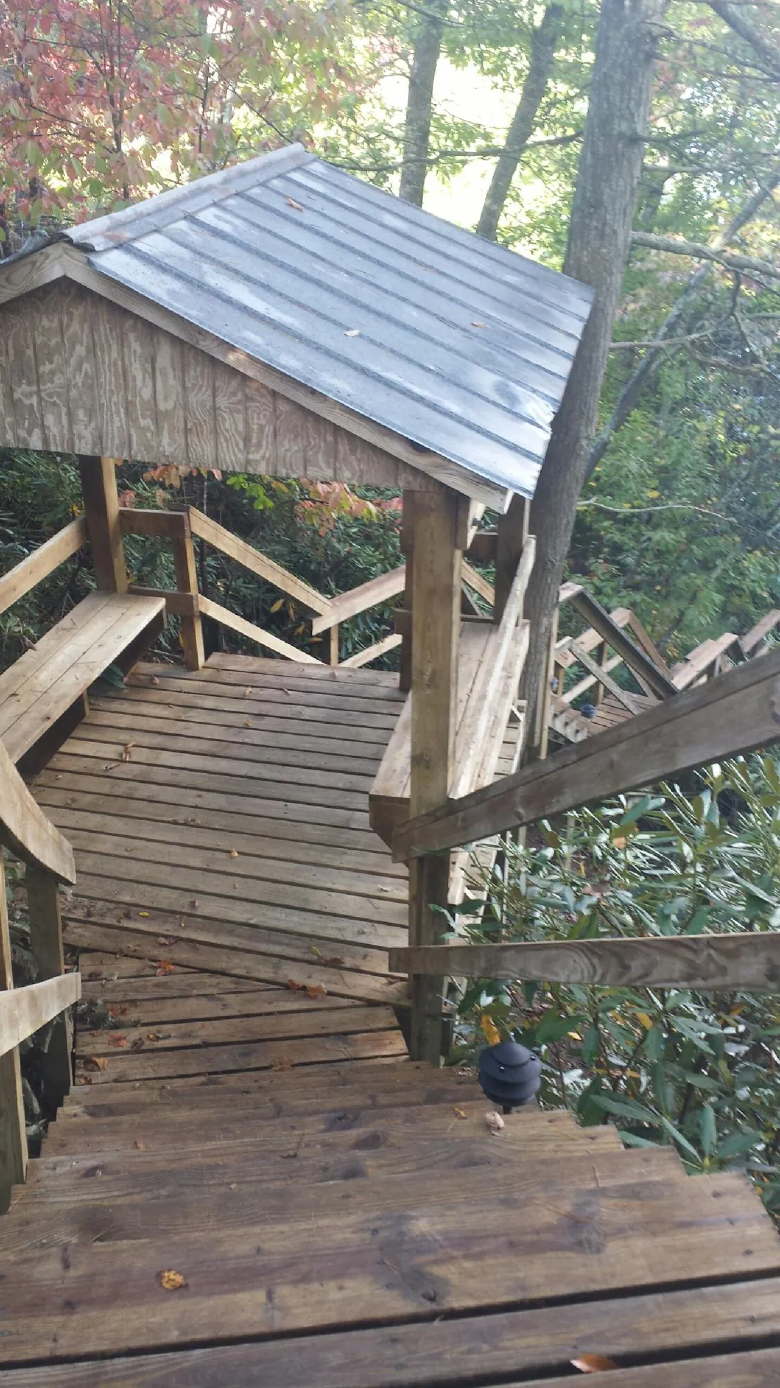 Metal roofed shelter over wooden steps on a wooded walkway — Skylight Repair & Installation work by our crew in Cornville