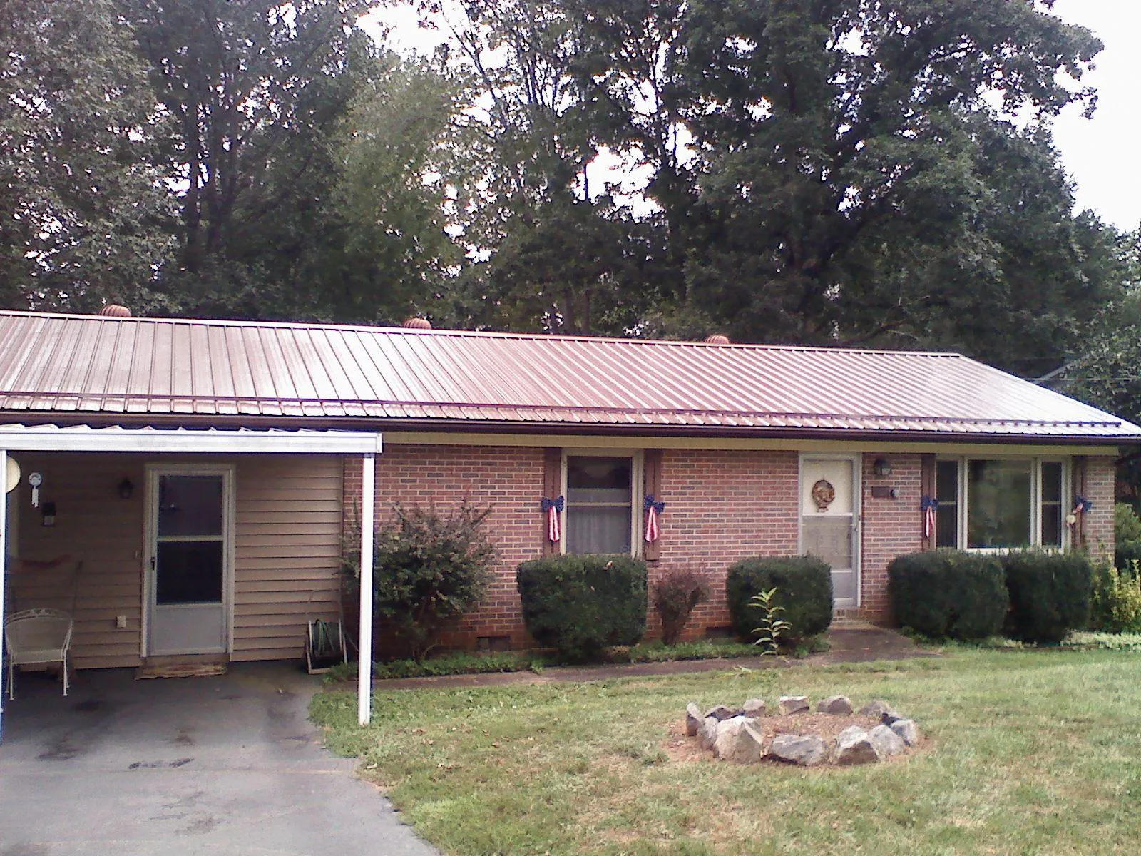 Bronze metal roof and carport on a brick ranch home — Roof Repair work by our crew in Cornville
