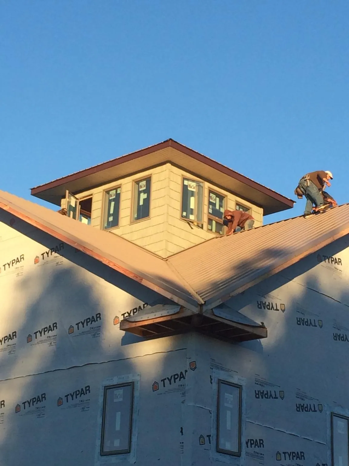 Roofers working around a rooftop cupola on a new metal roof at sunset — Roof Waterproofing in Cornville by Roofing Brothers